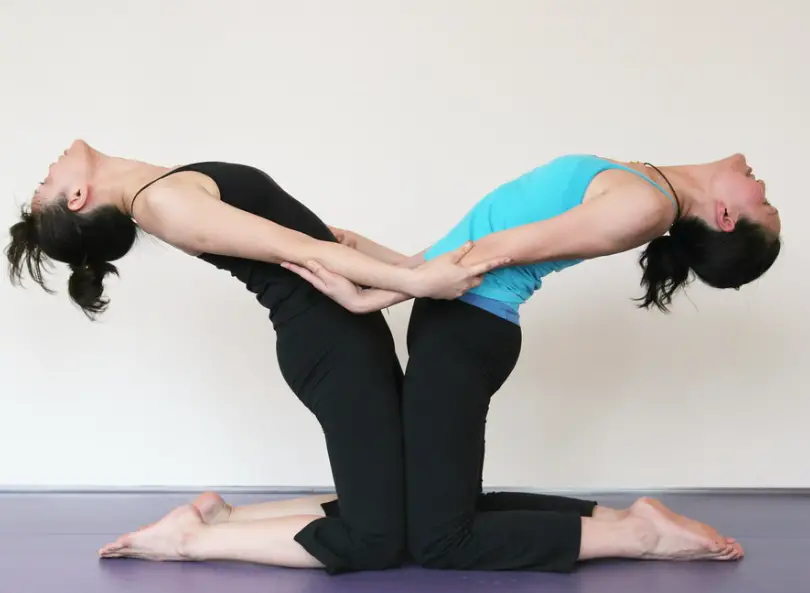 Two women doing the double camel yoga pose
