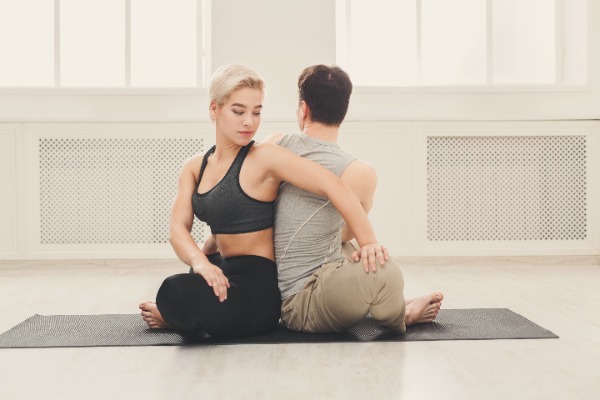 Man and woman doing partner twist yoga pose